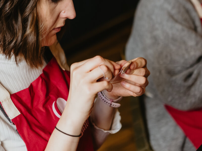 A woman is sewing a small felt sloth by hand
