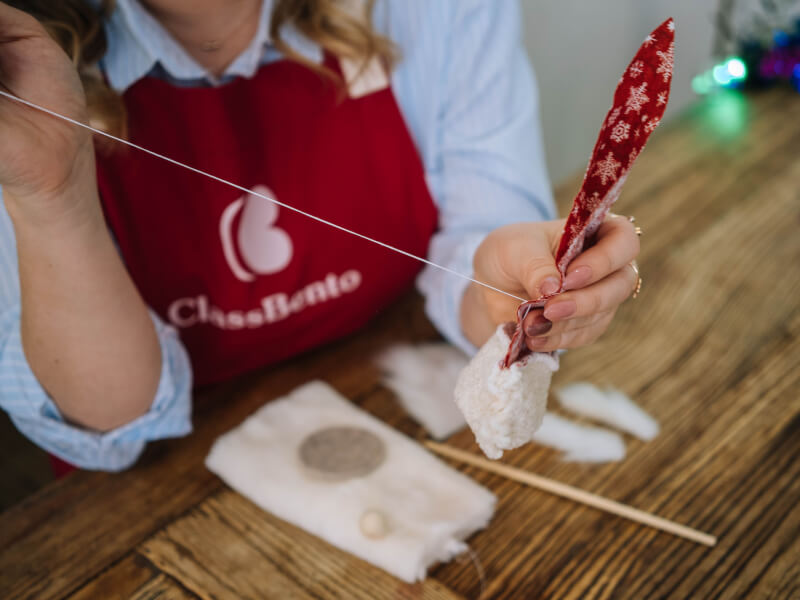 A close up of a person hand sewing red and white fabric together