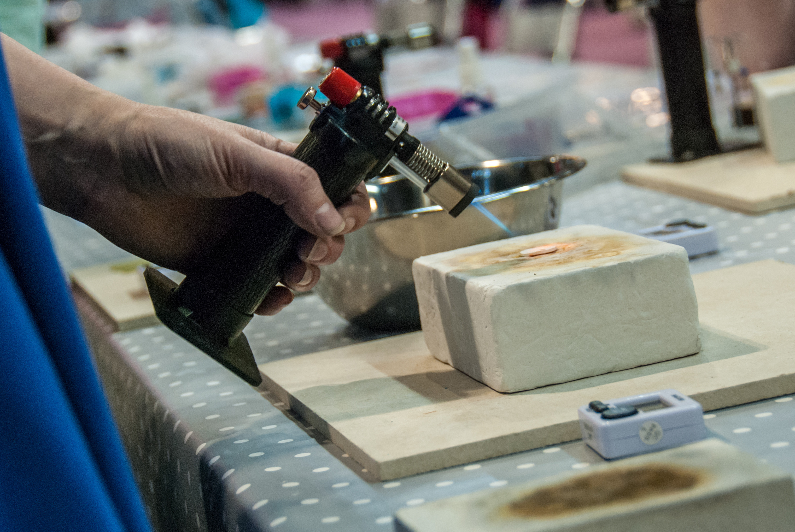A close up shot of a person heating silver clay with a blowtorch