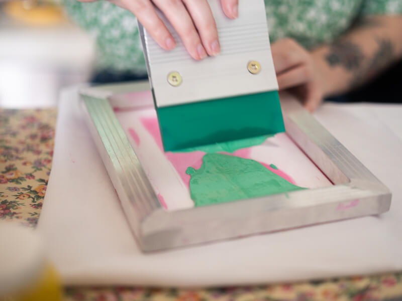 A person applying green ink to a silk screen