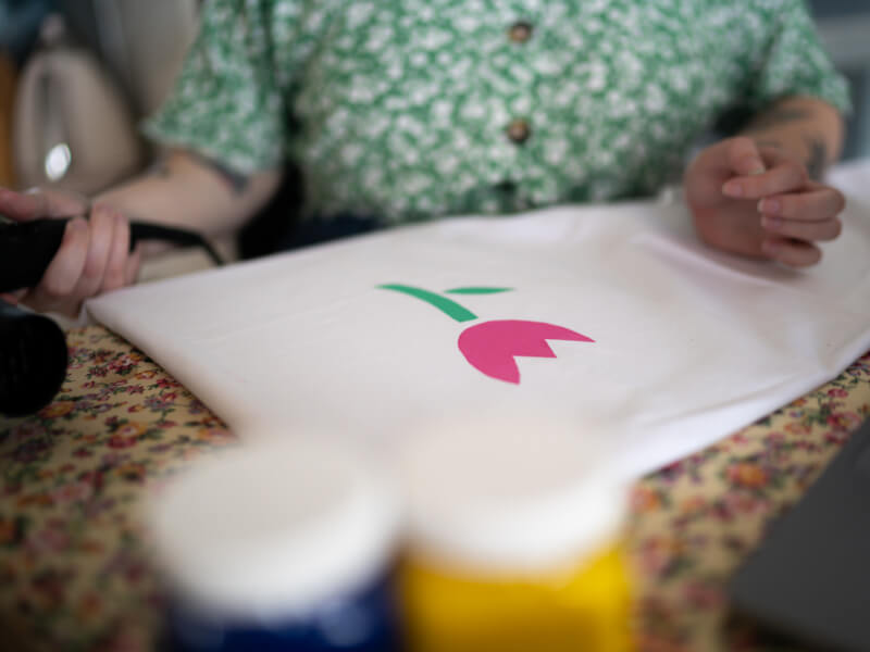 A close up of a pink and green screen printed flower on white fabric