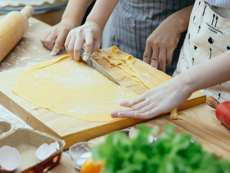 Two people in a kitchen learning how to make Italian pasta