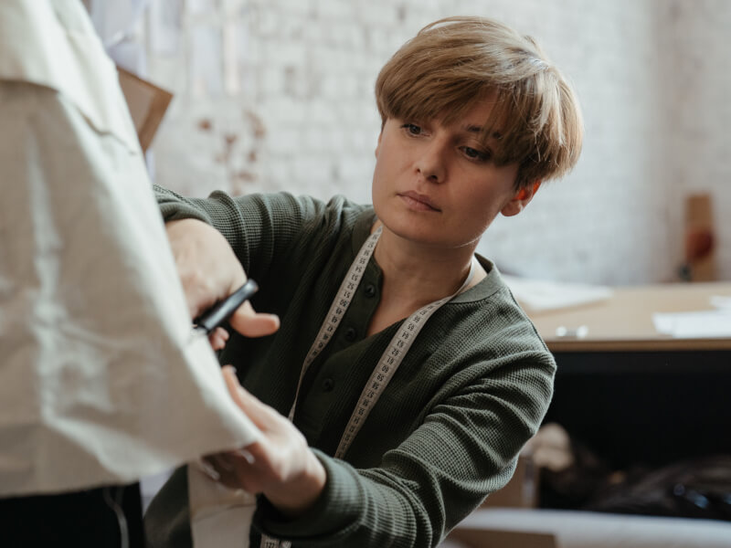 A person is cutting beige fabric on a tailors dummy at a sewing and embroidery class in Manchester