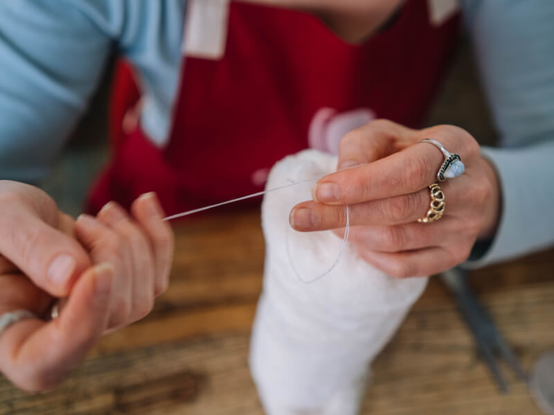 A close up of a person sewing fabric with white cotton at a Manchester and embroidery sewing class