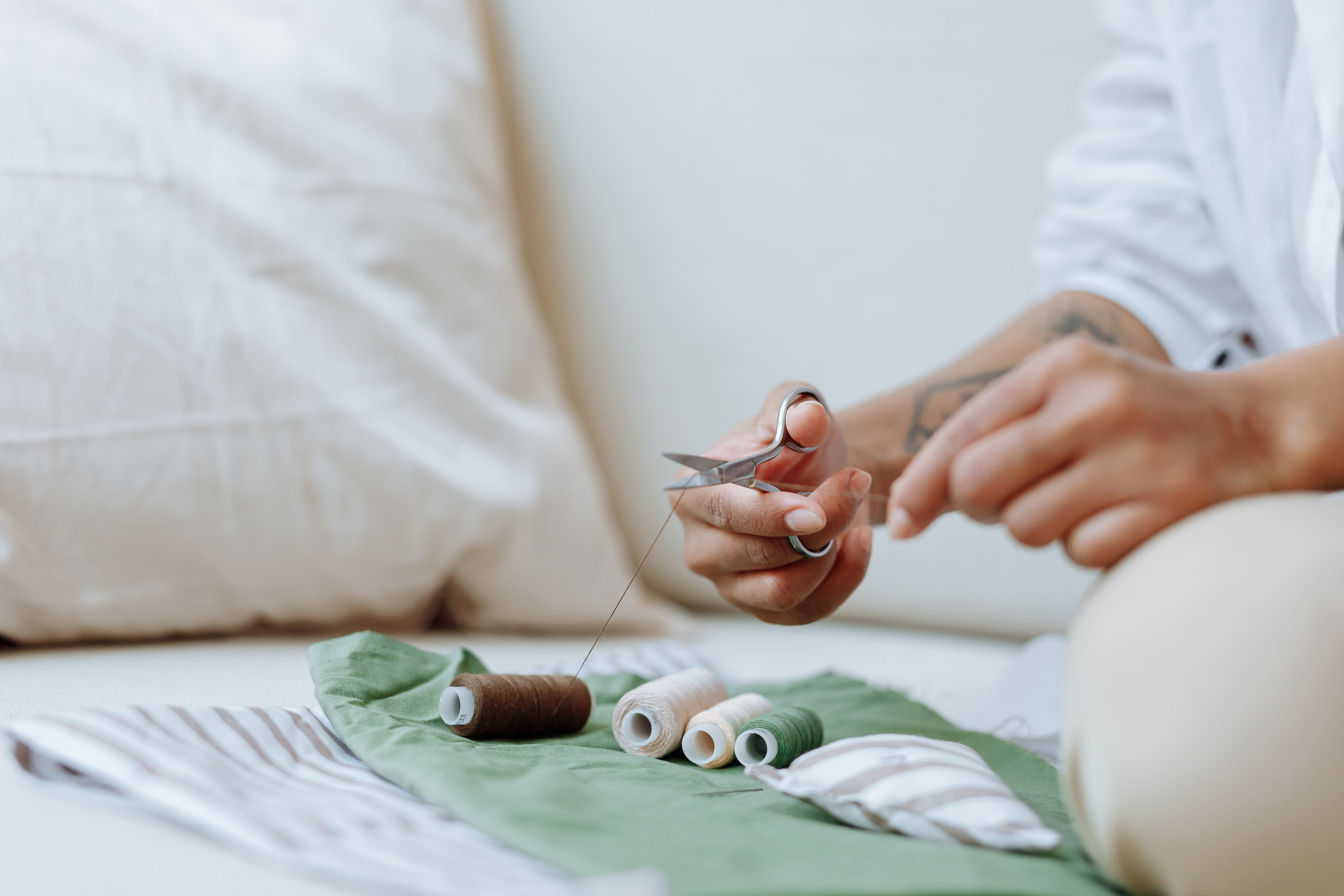 A person is cutting brown thread over a table covered in green fabric
