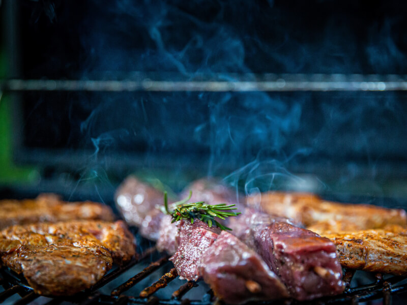 Several pieces of meat cooking on a barbecue 
