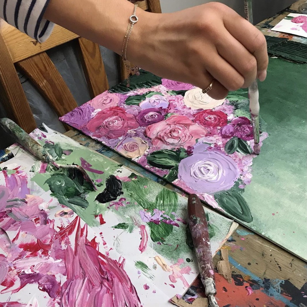 Close up of a person making a thick impasto floral painting