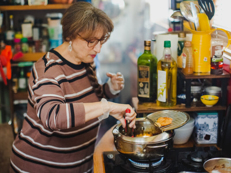 A woman on a houseboat is making churros in a pan