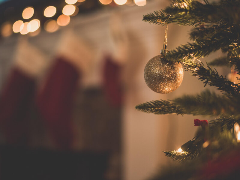 A golden bauble hanging from a christmas tree