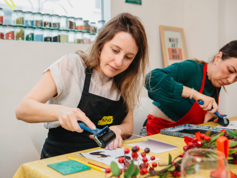 A woman is inking a lino block at a block printing class