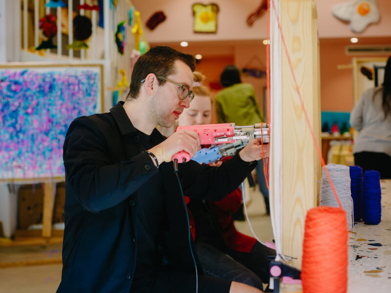 Man using a tufting gun in a rug tufting class