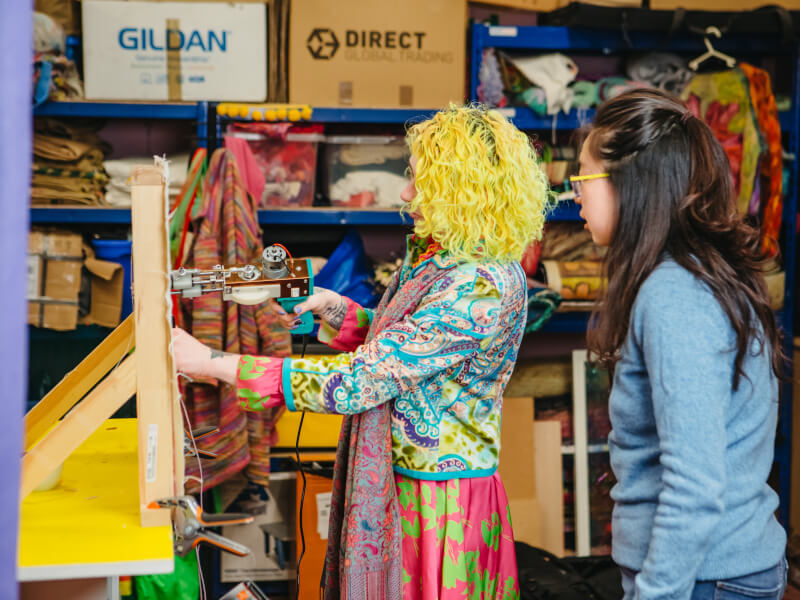 Two people in a tufting class using a tufting gun