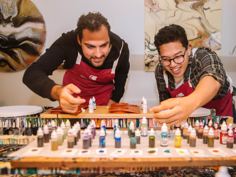 Two men choosing colours to use in an acrylic pouring project