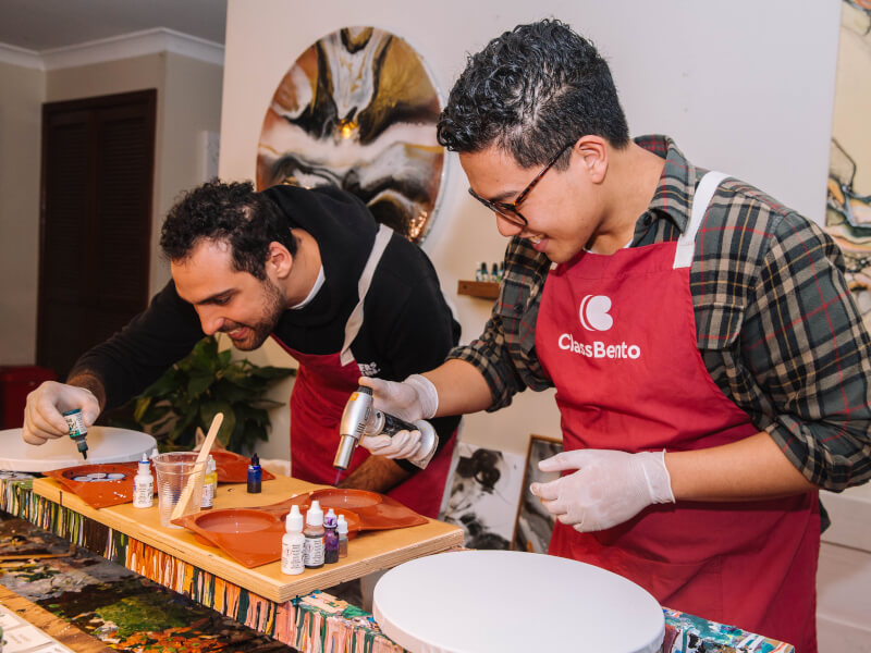 Two men are mixing colours at a paint pouring class