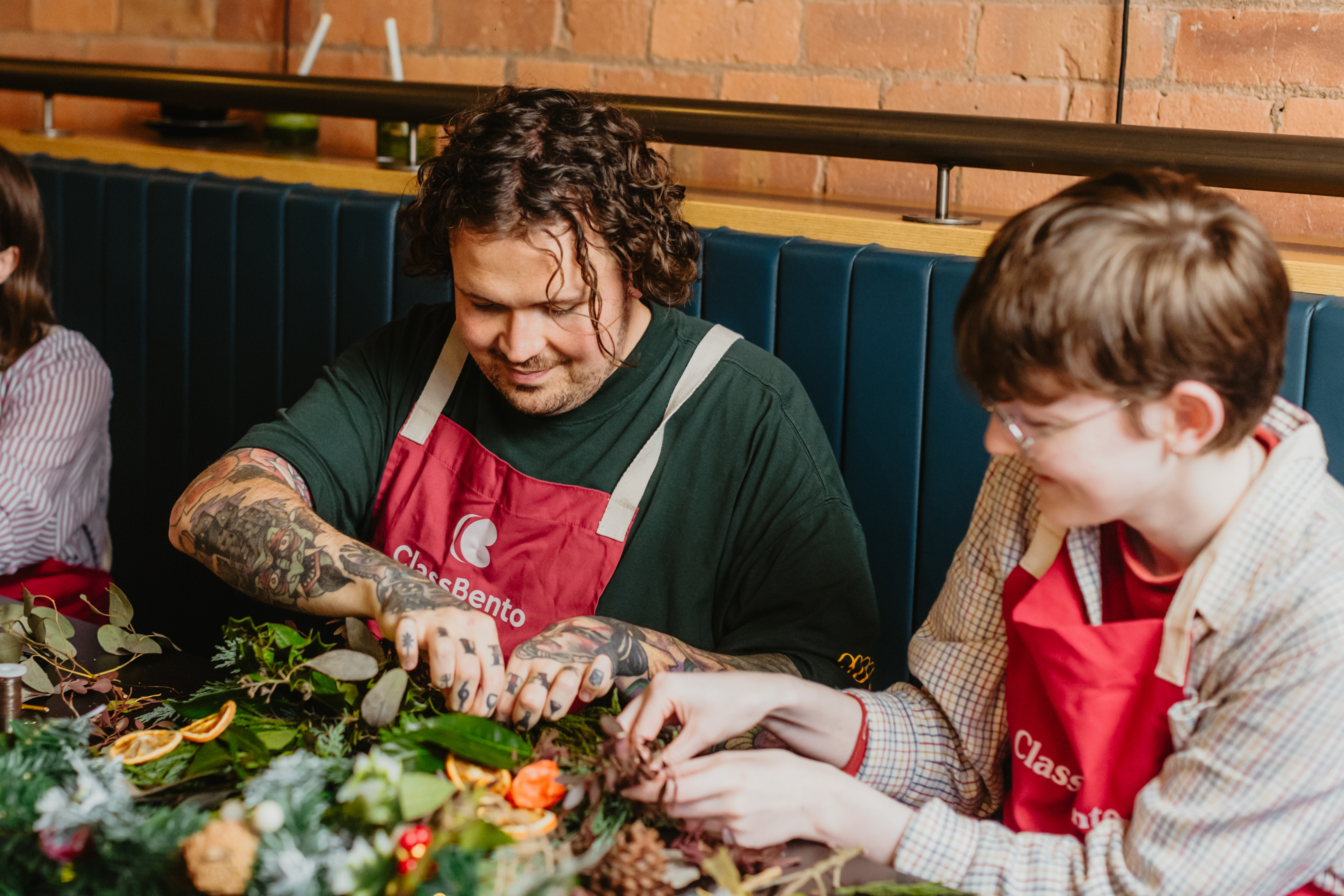 Two people choosing greenery at a Christmas wreath making workshop