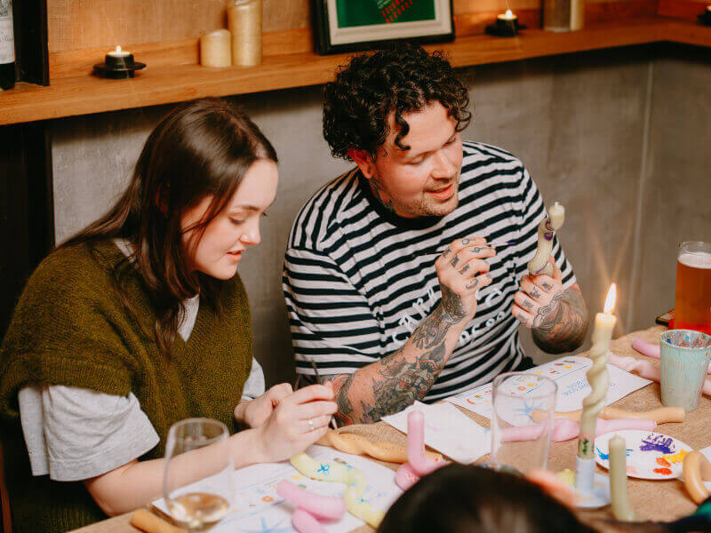 Two people are making and decorating bendy candles