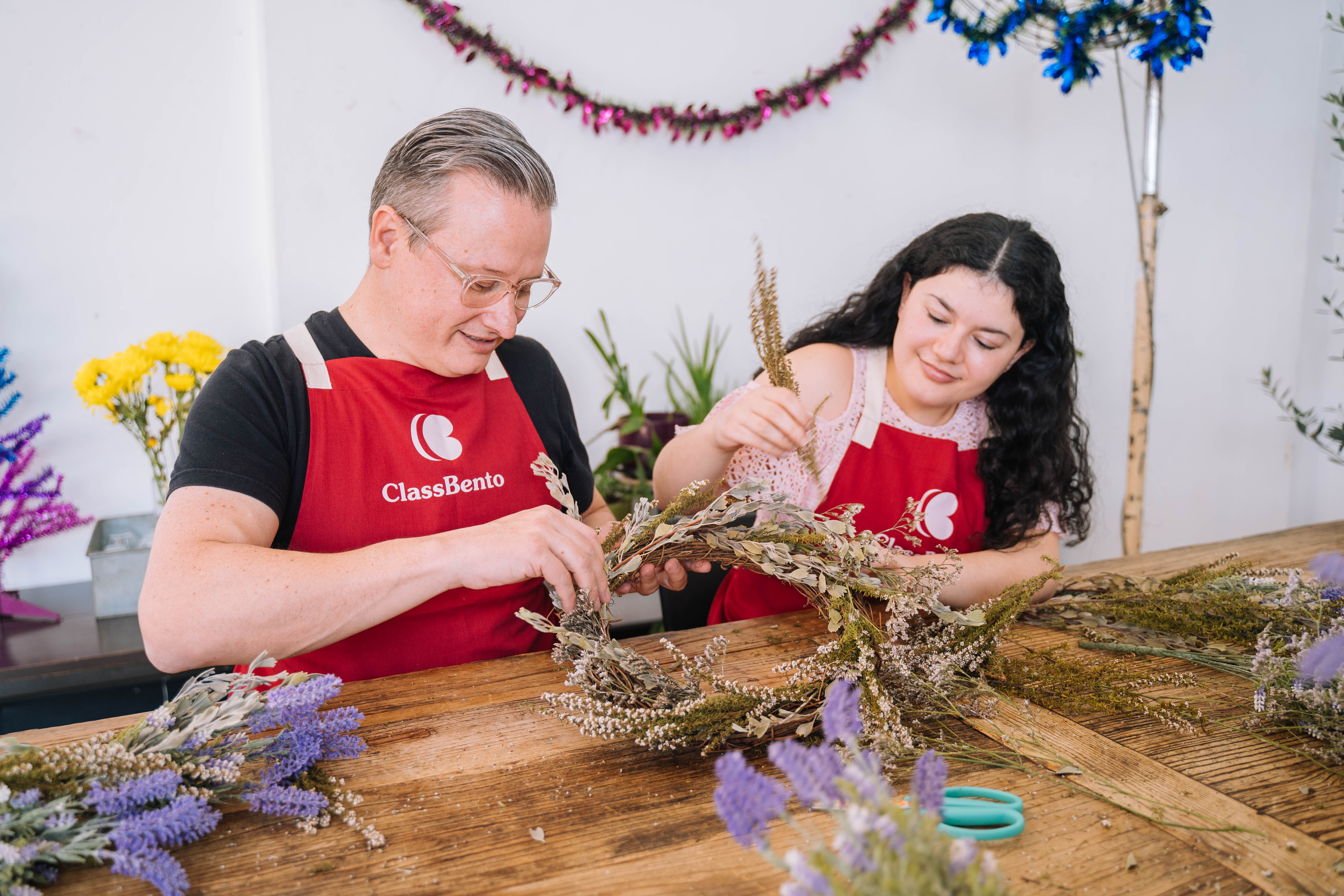 Two people making a Christmas wreath together
