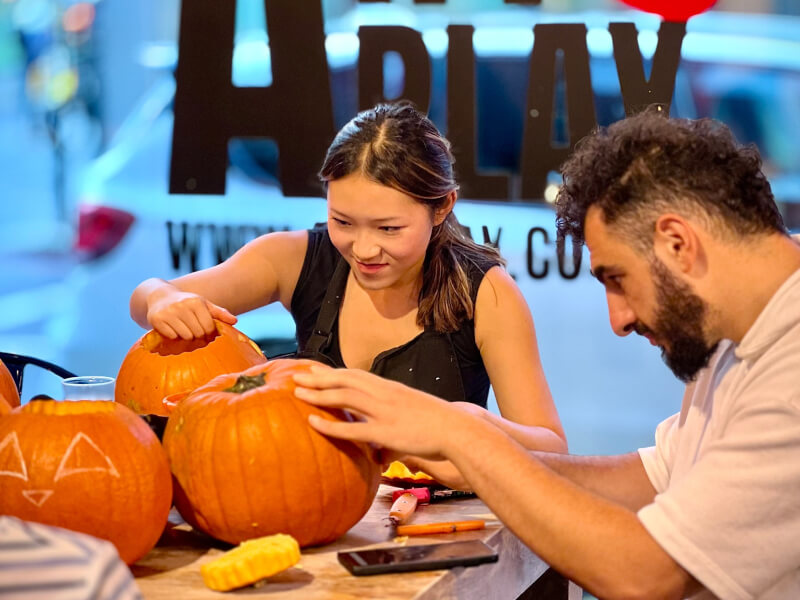 Two people carving pumpkins at a Halloween class