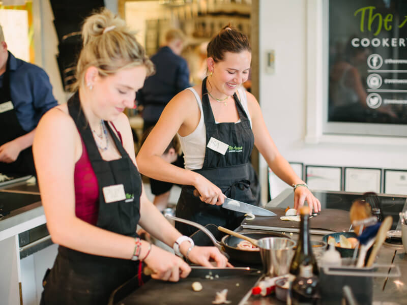 Two women chopping onions at a cooking class