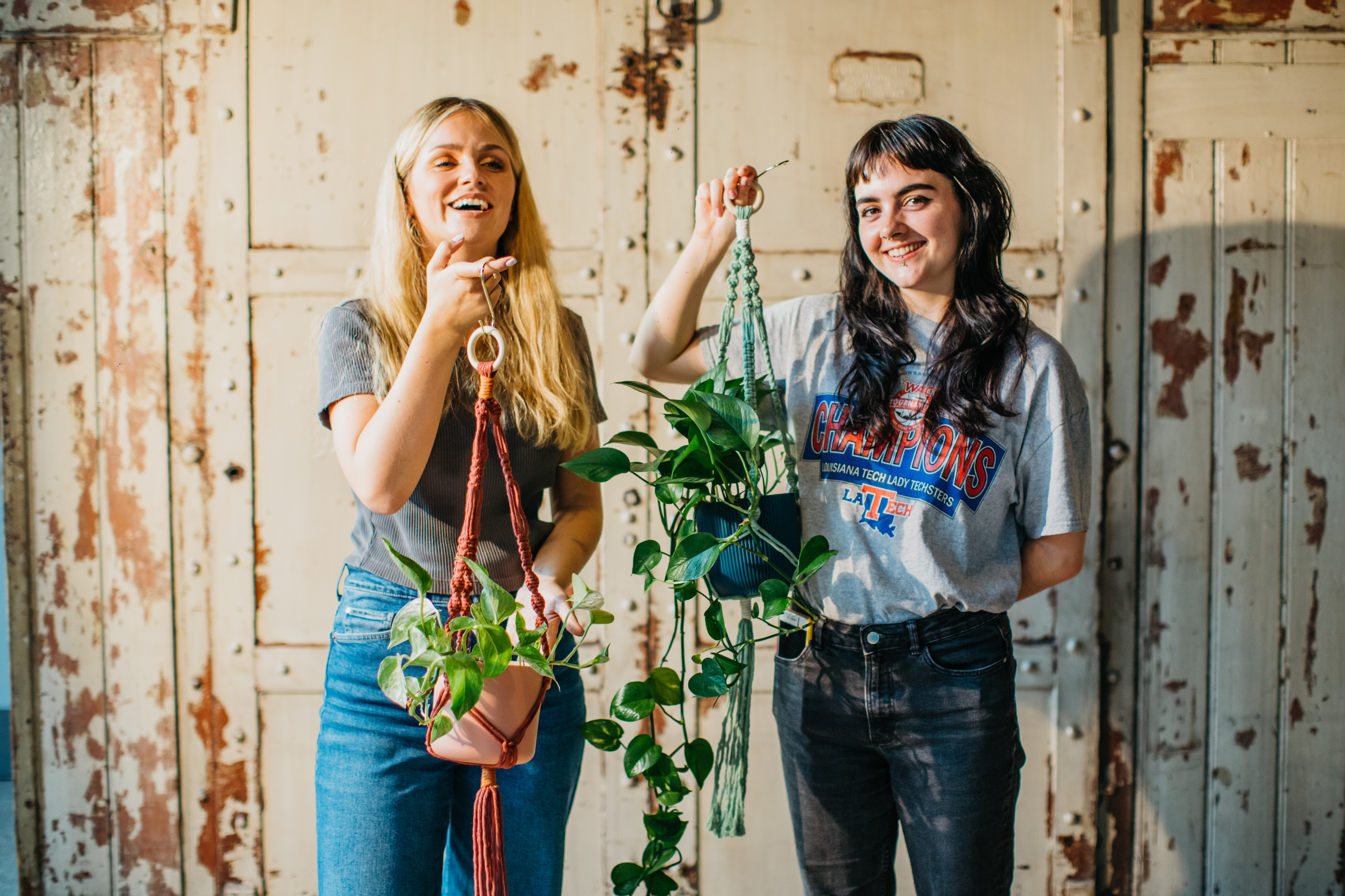 Two women holding handmade macrame planters and smiling