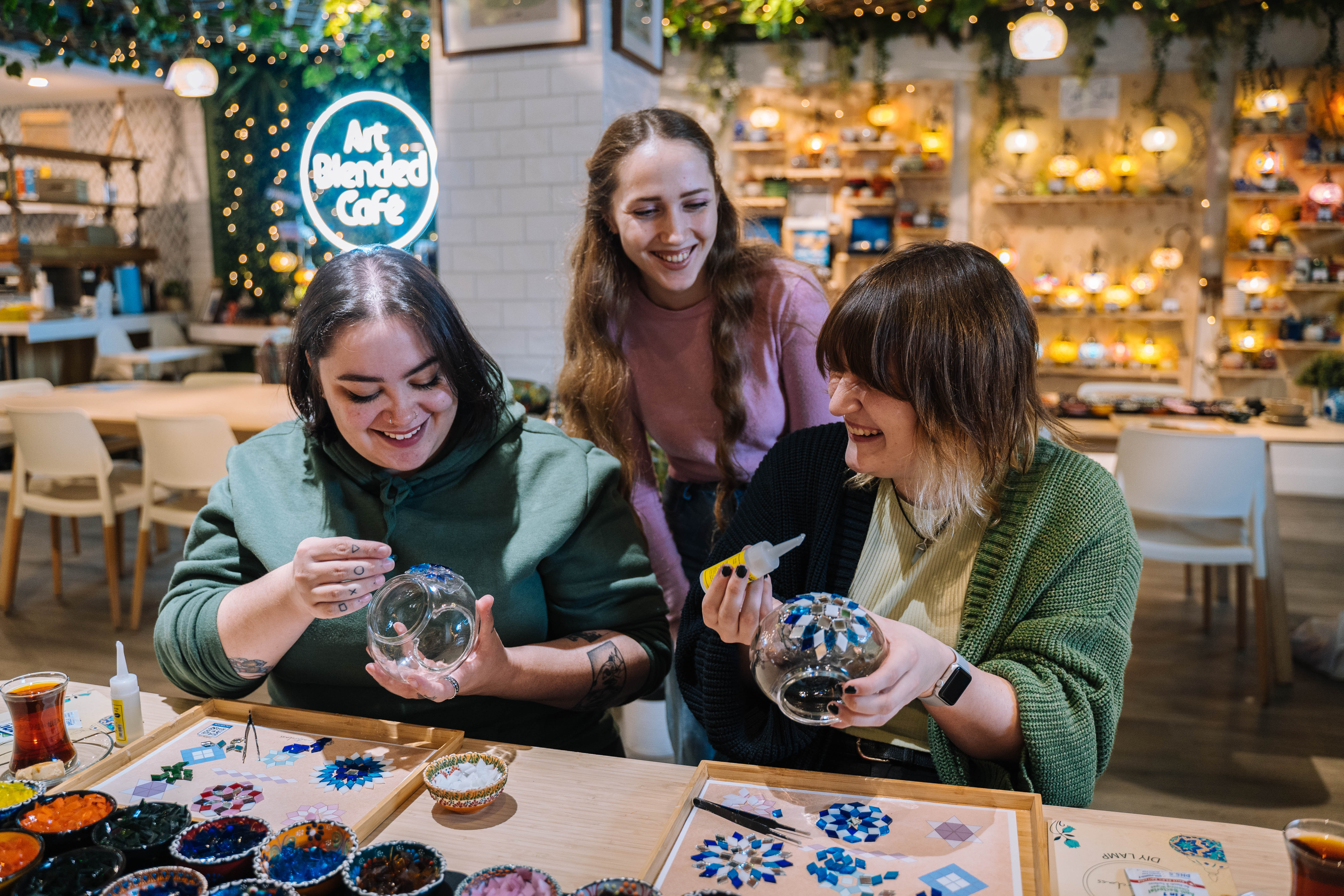 Two women learning how to make mosaic lamps 