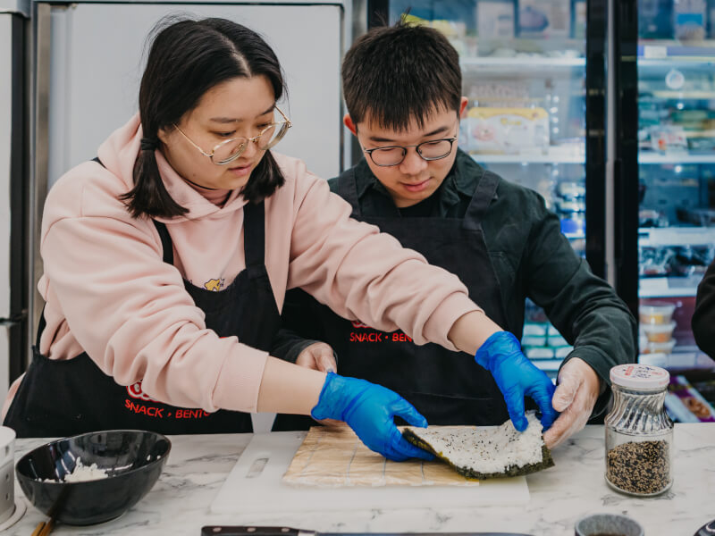 Two people making sushi at a cooking class in London
