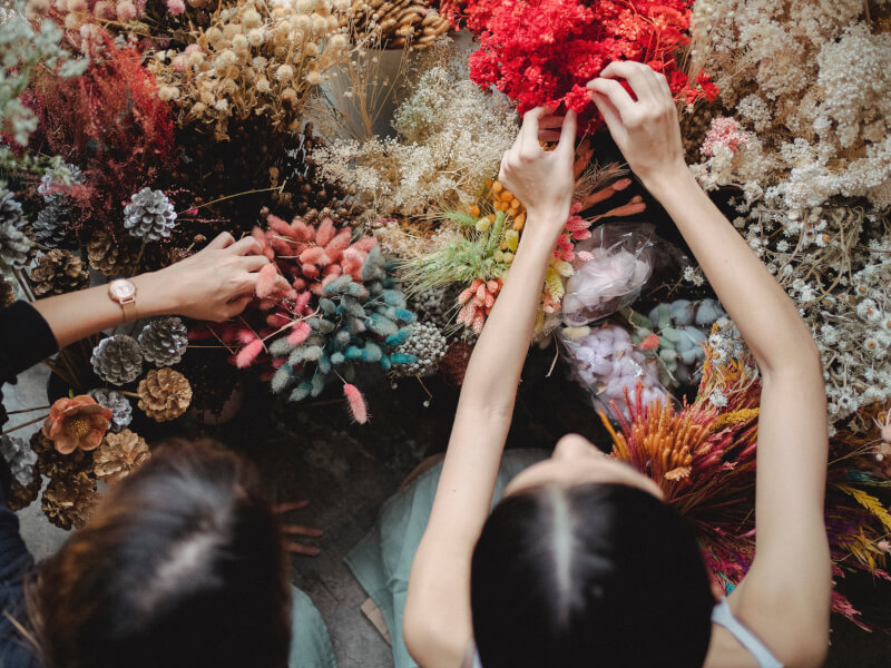 Two women, pictured from above, choose flowers from a large selection
