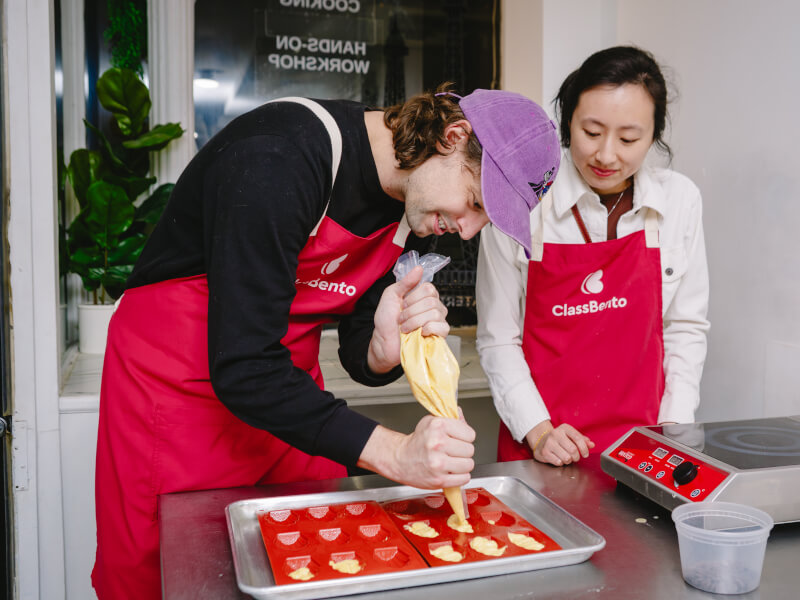 Two people piping chocolate into a mould