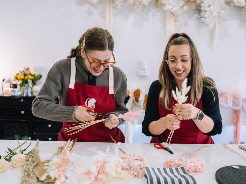 Two women arranging dried flowers