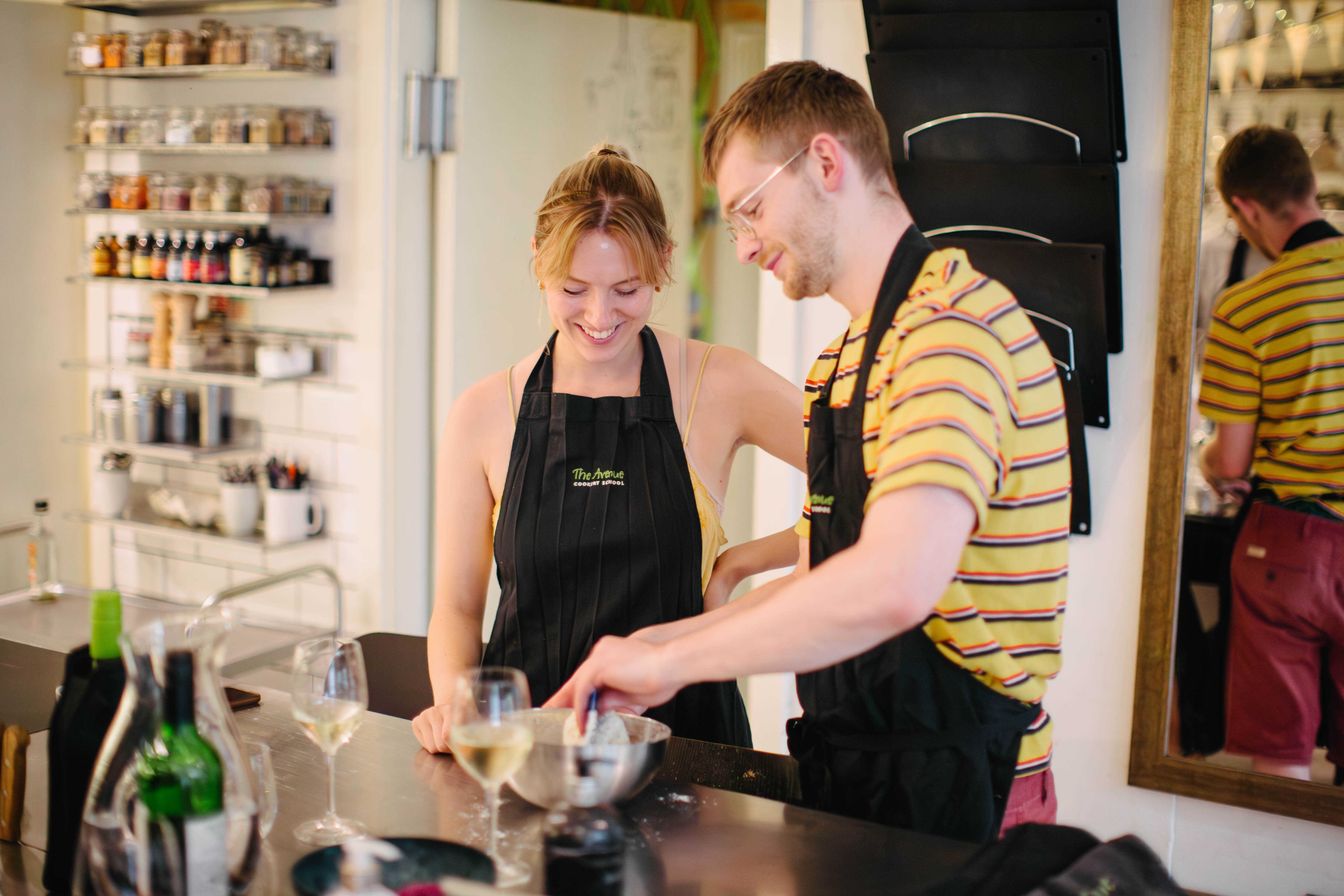 A man and a woman at a cooking class, adding ingredients to a bowl