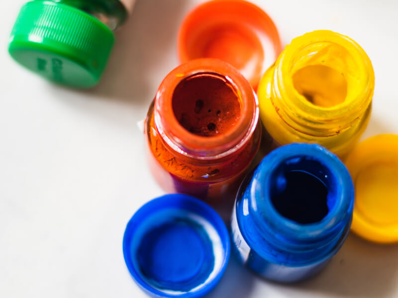 A flatlay image of red, blue, green and yellow open paint pots