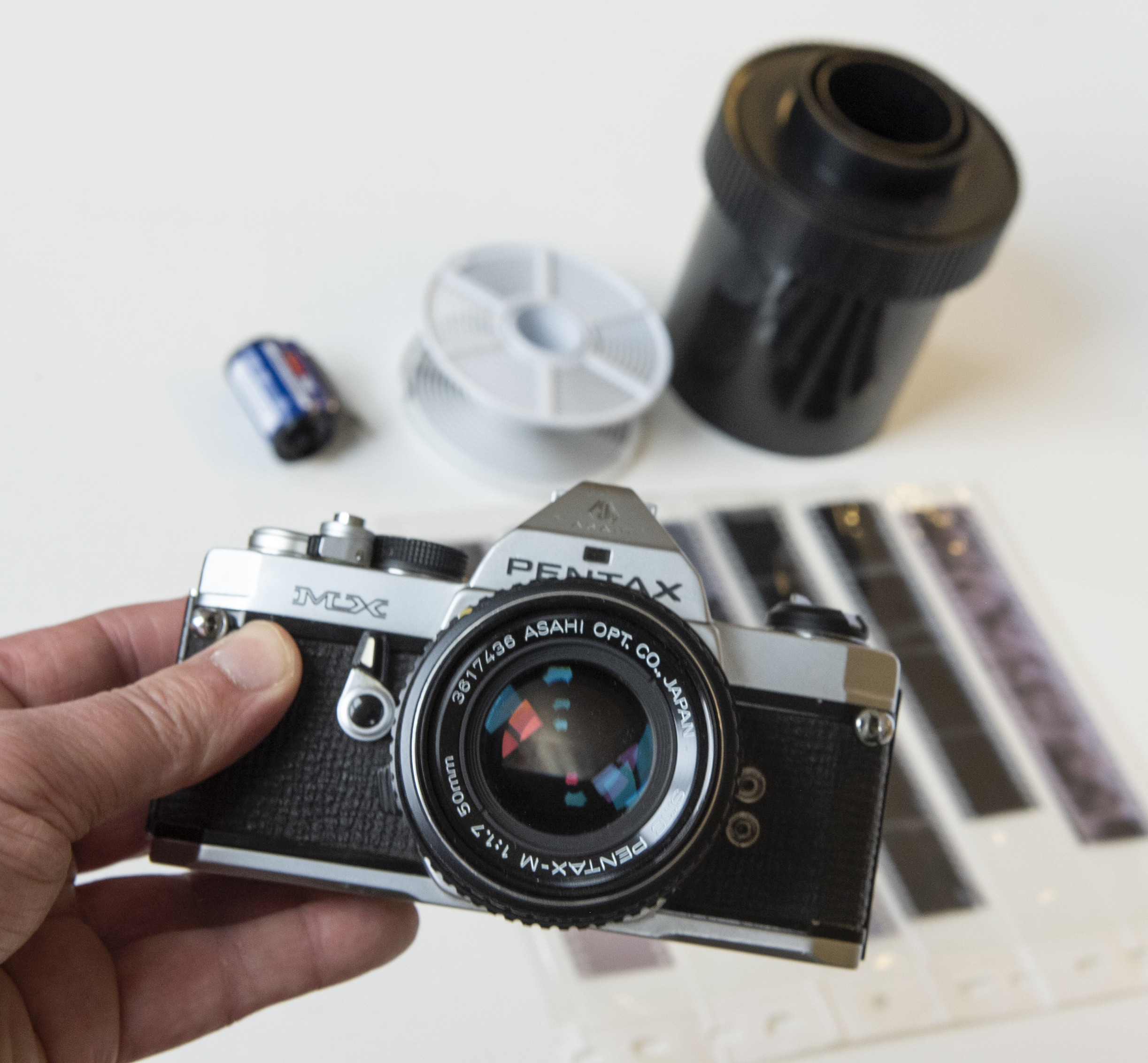 A close up of a person holding a vintage Pentax SLR camera
