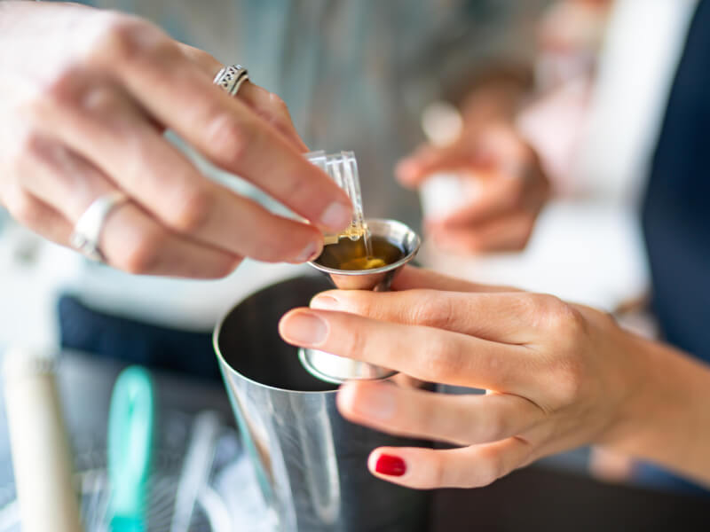 A close up of a person pouring alcohol into a shot measure
