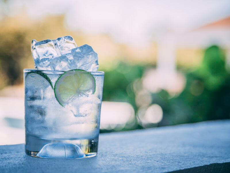 Gin with ice and lime with blue sky background.