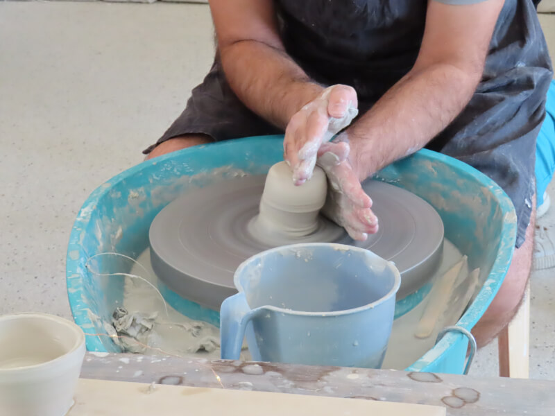 A close up of a persons hands shaping clay on a pottery wheel