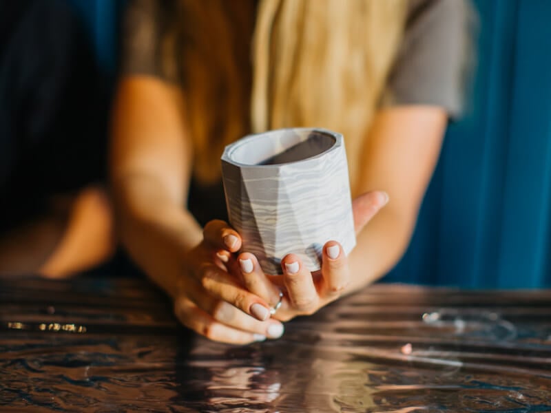 A woman's hands holding a grey resin handmade plant pot