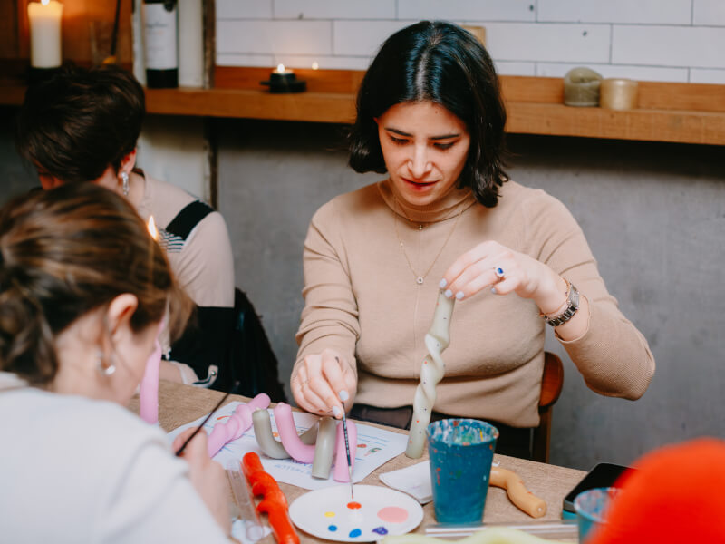 A woman painting bendy candles with coloured spots