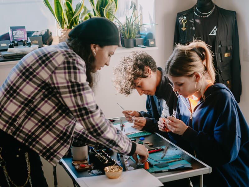 Woman teaching jewellery making to two people