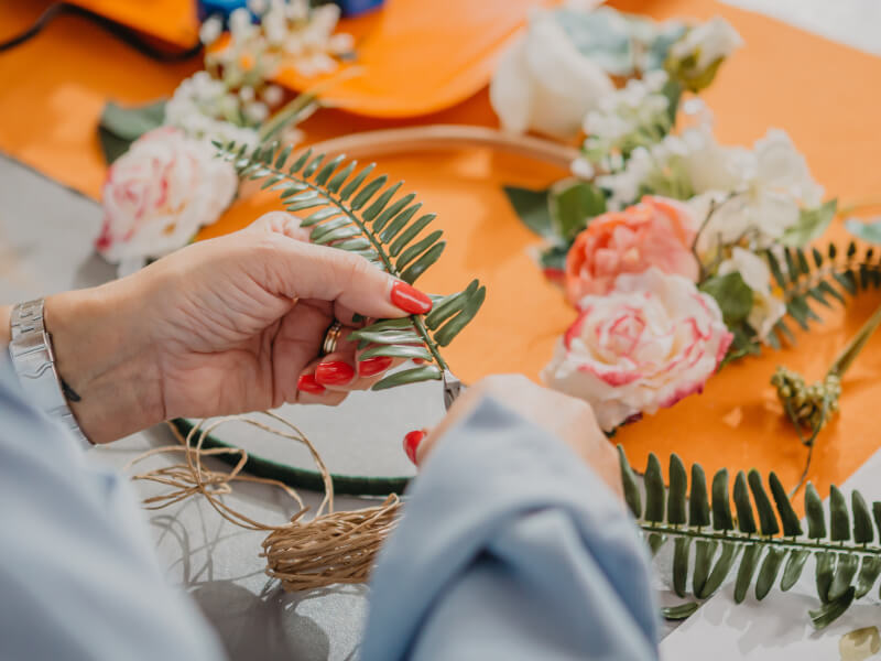 A close up of a woman making a floral hoop