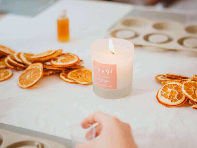 A burning candle with orange slices 